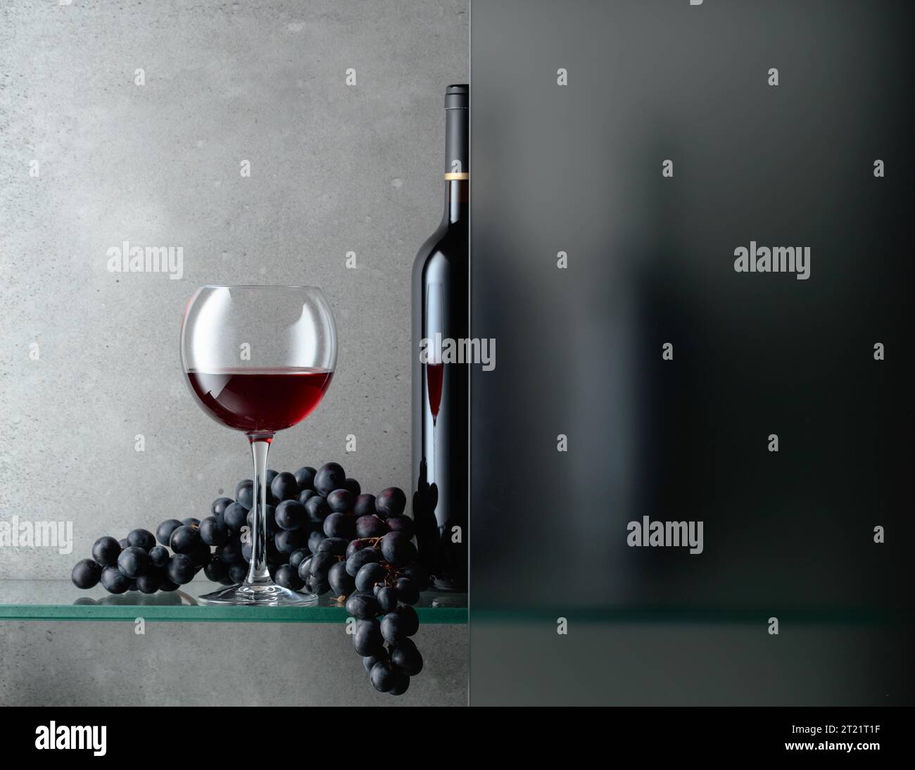 Bottle and a glass of red wine with a bunch of grapes. The still life ...
