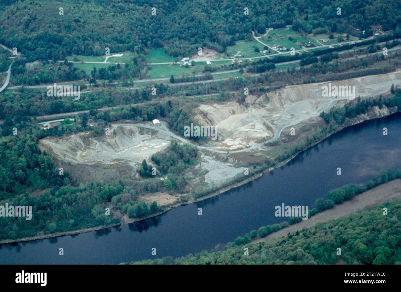 Aerial view of sand and gravel mine at edge of river, showing environmental damage hidden from