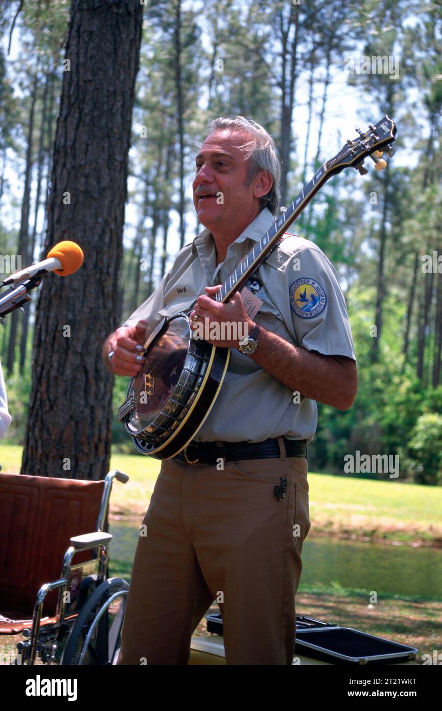 Fish and Wildlife Service volunteer with logo playing banjo during Okefenokee refuge celebration. Vertical. Subjects: Volunteers;Wildlife refuges. Location: Georgia. Fish and Wildlife Service Site: OKEFENOKEE NATIONAL WILDLIFE REFUGE.   Collection: Wildlife Refuges. Stock Photo