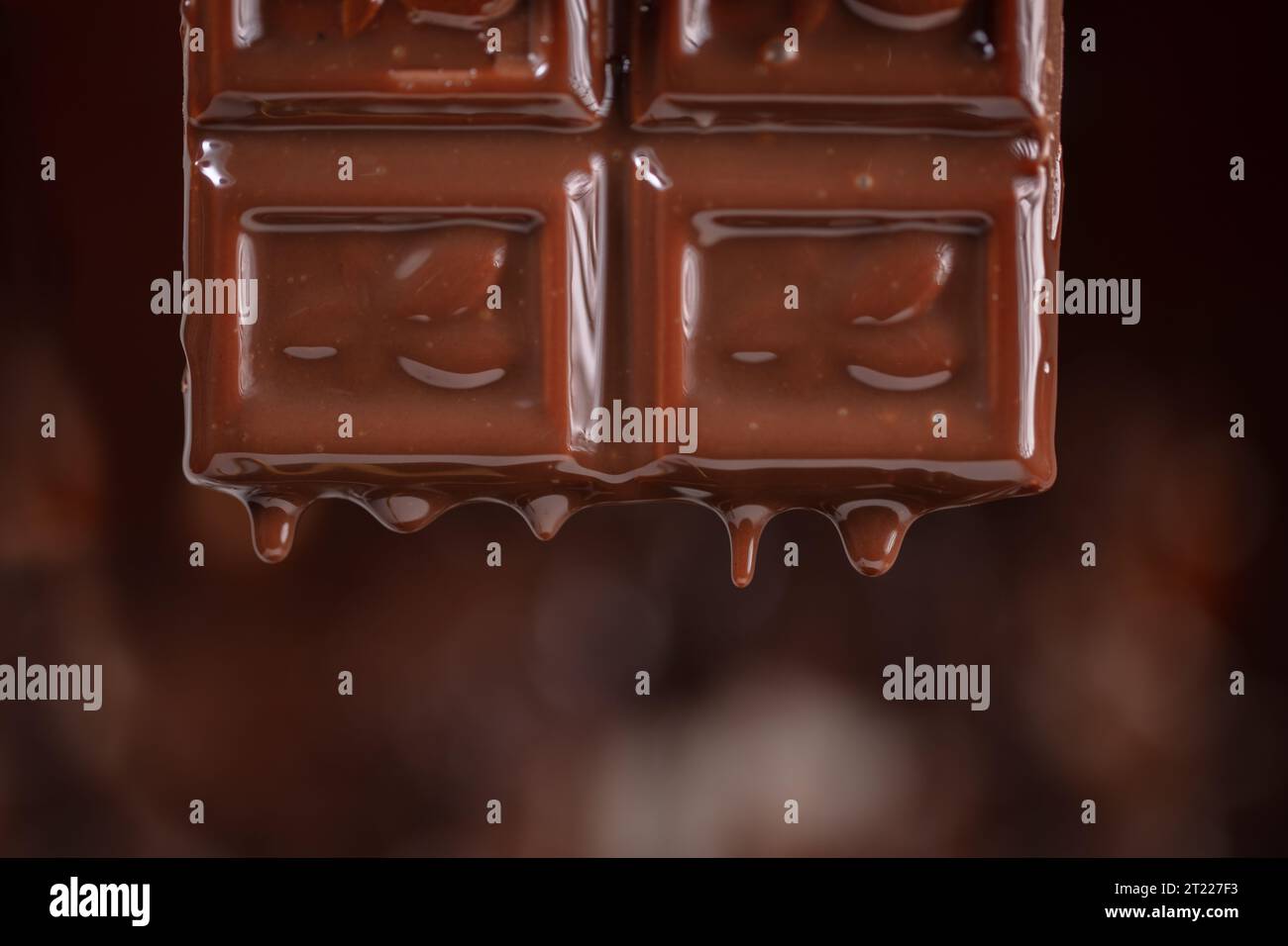 Melted chocolate drips down on a brown background. Stock Photo