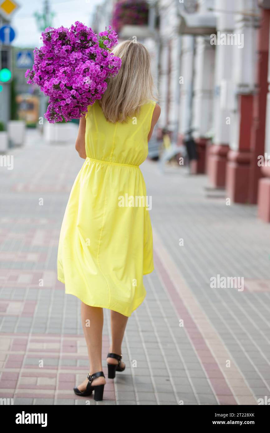 A woman is walking down the street with a huge bouquet of flowers ...