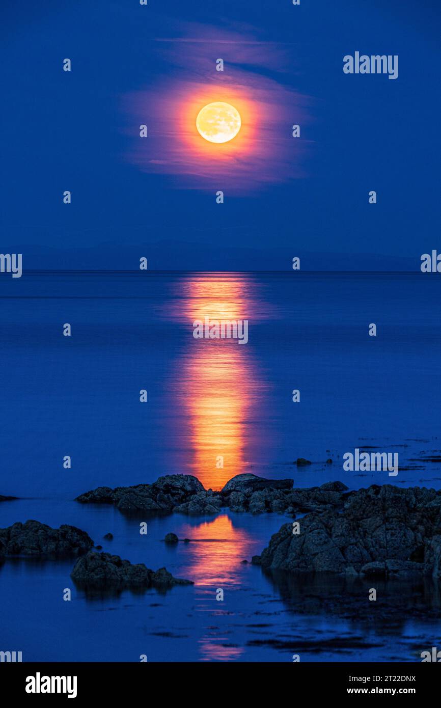 The super moon (a blue moon) on 30/8/2023 rising over the Isle of Arran seen from the Kintyre Peninsula, Scotland UK Stock Photo