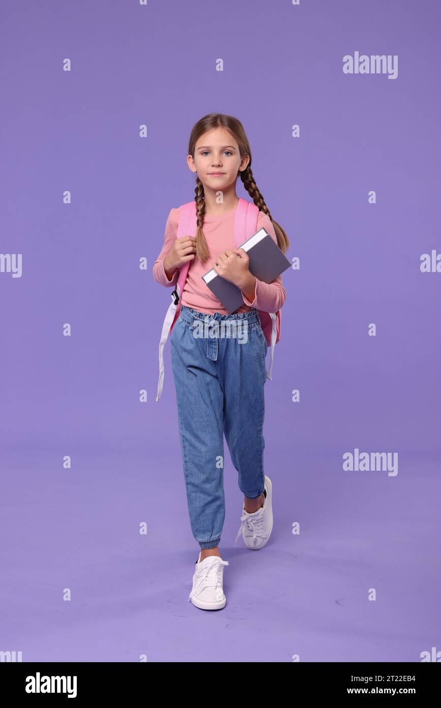 Cute schoolgirl with books on violet background Stock Photo - Alamy