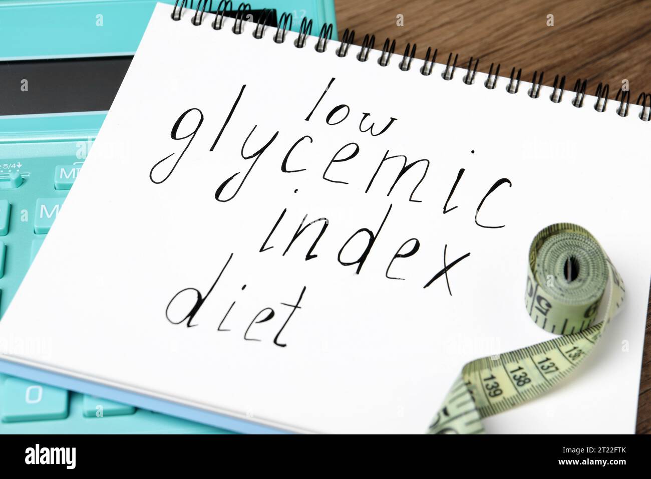Notebook with words Low Glycemic Index Diet, measuring tape and calculator on table, closeup Stock Photo