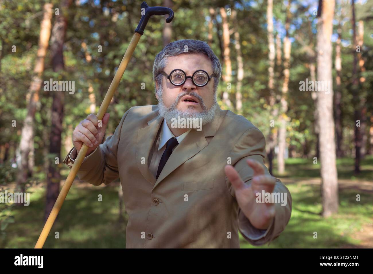 Funny old man with a stick. An elderly man with a walking stick with a funny face. The man has a funny face with a beard. Stock Photo