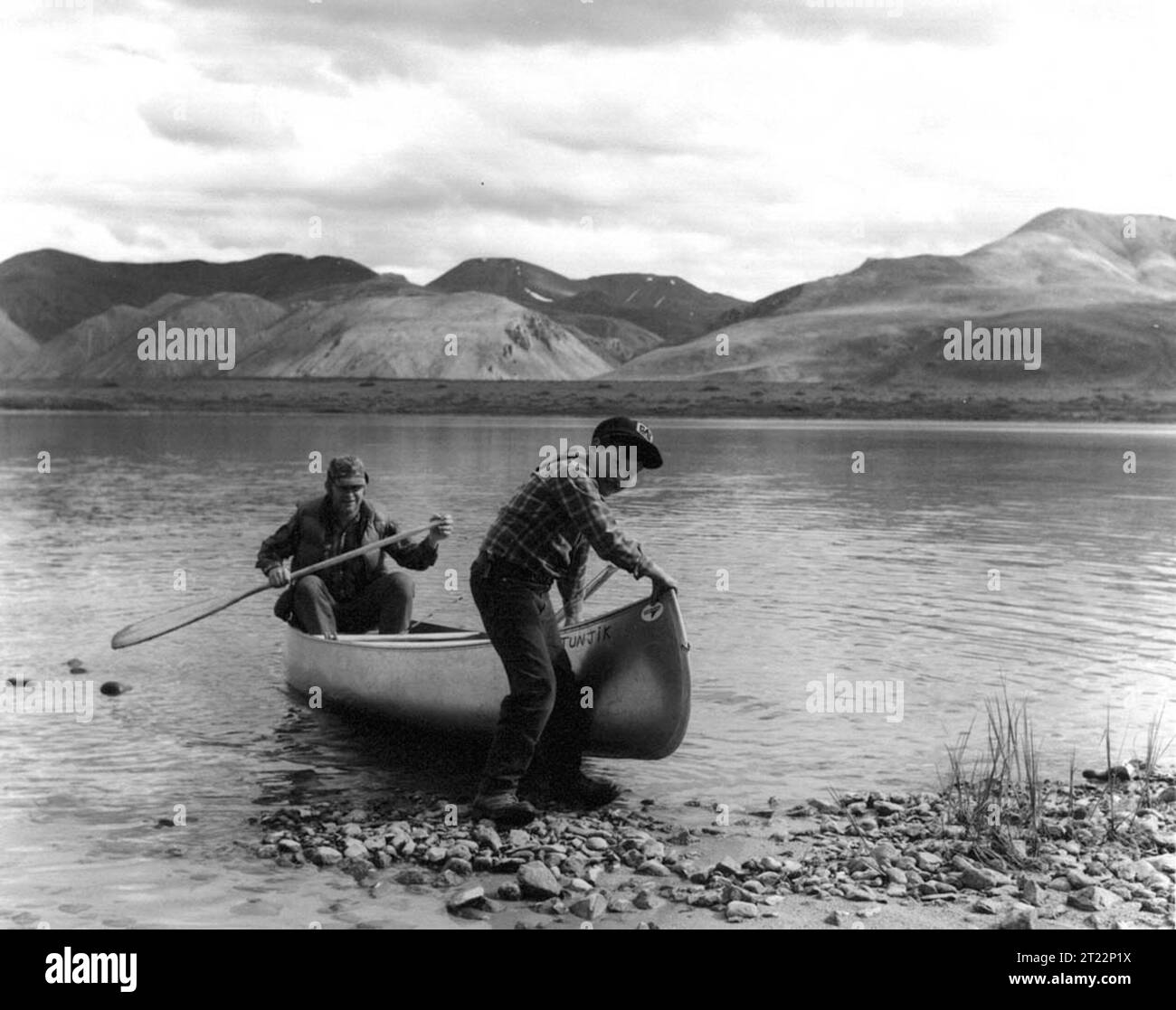 Black And White Image Of A Man And Boy Coming Ashore By Canoe On The Black and white image of a man and boy coming ashore by canoe on the