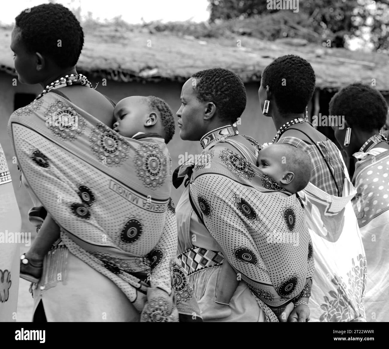 Tribal women of Maasai Mara wearing their traditional dress carrying their kids and entertaining the visitors in their village Stock Photo