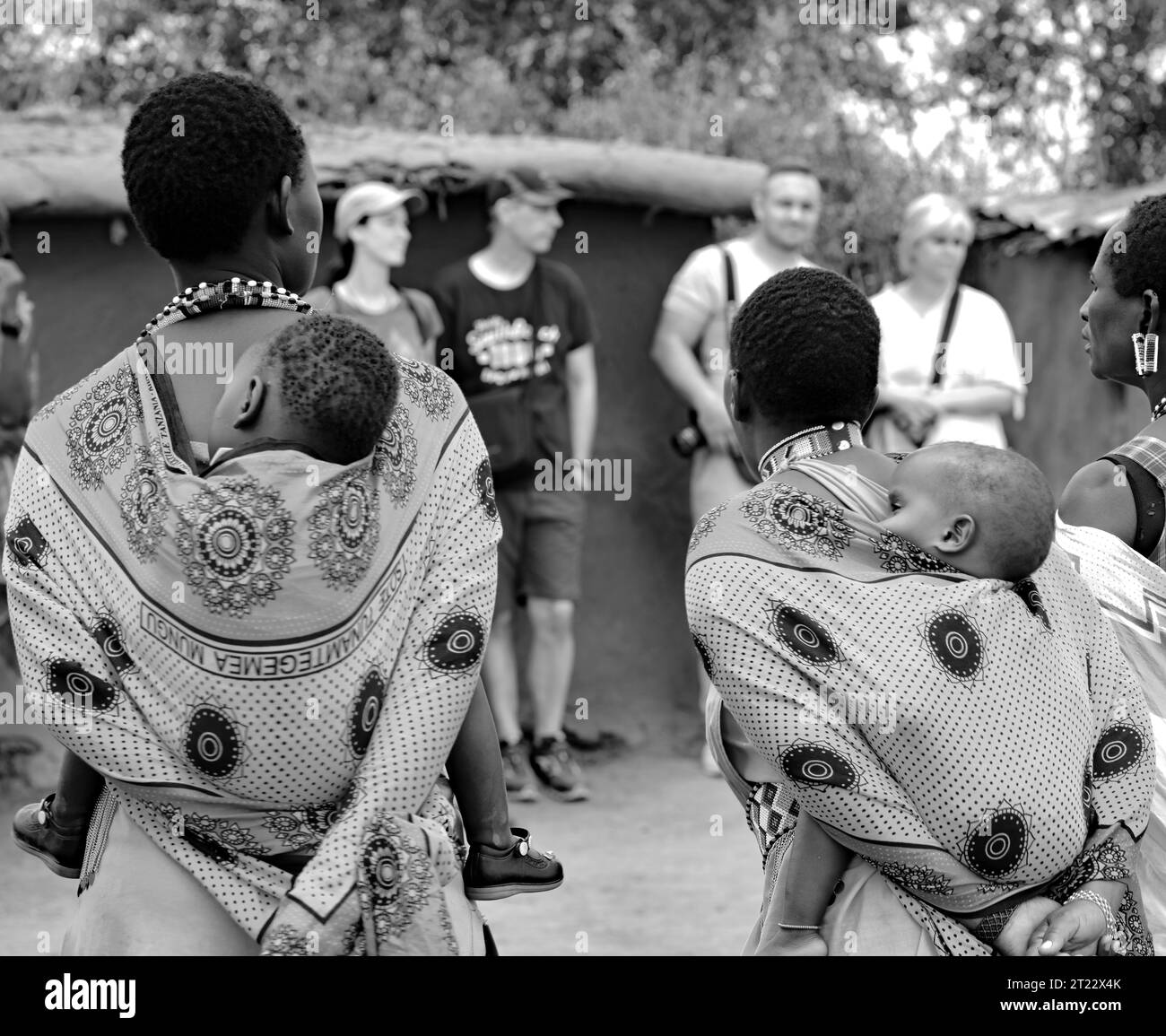 Tribal women of Maasai Mara wearing their traditional dress carrying their kids and entertaining the visitors in their village Stock Photo