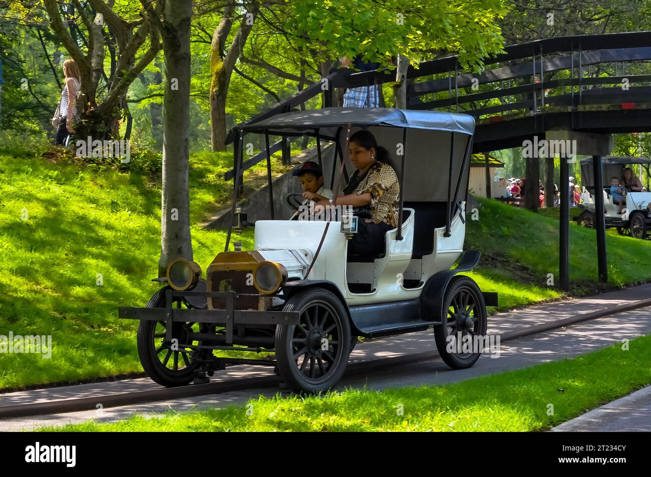 Mother and son riding a recreational vehicle in Centre Island. Amusement park ride with the resemblance of a vintage car Stock Photo