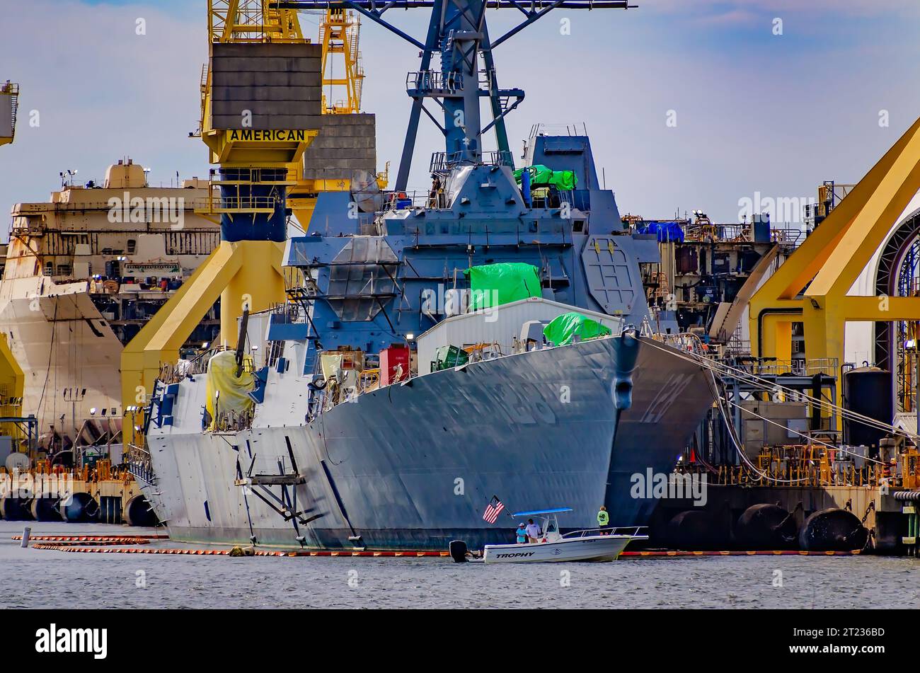 People fish near military warships under construction at Ingalls