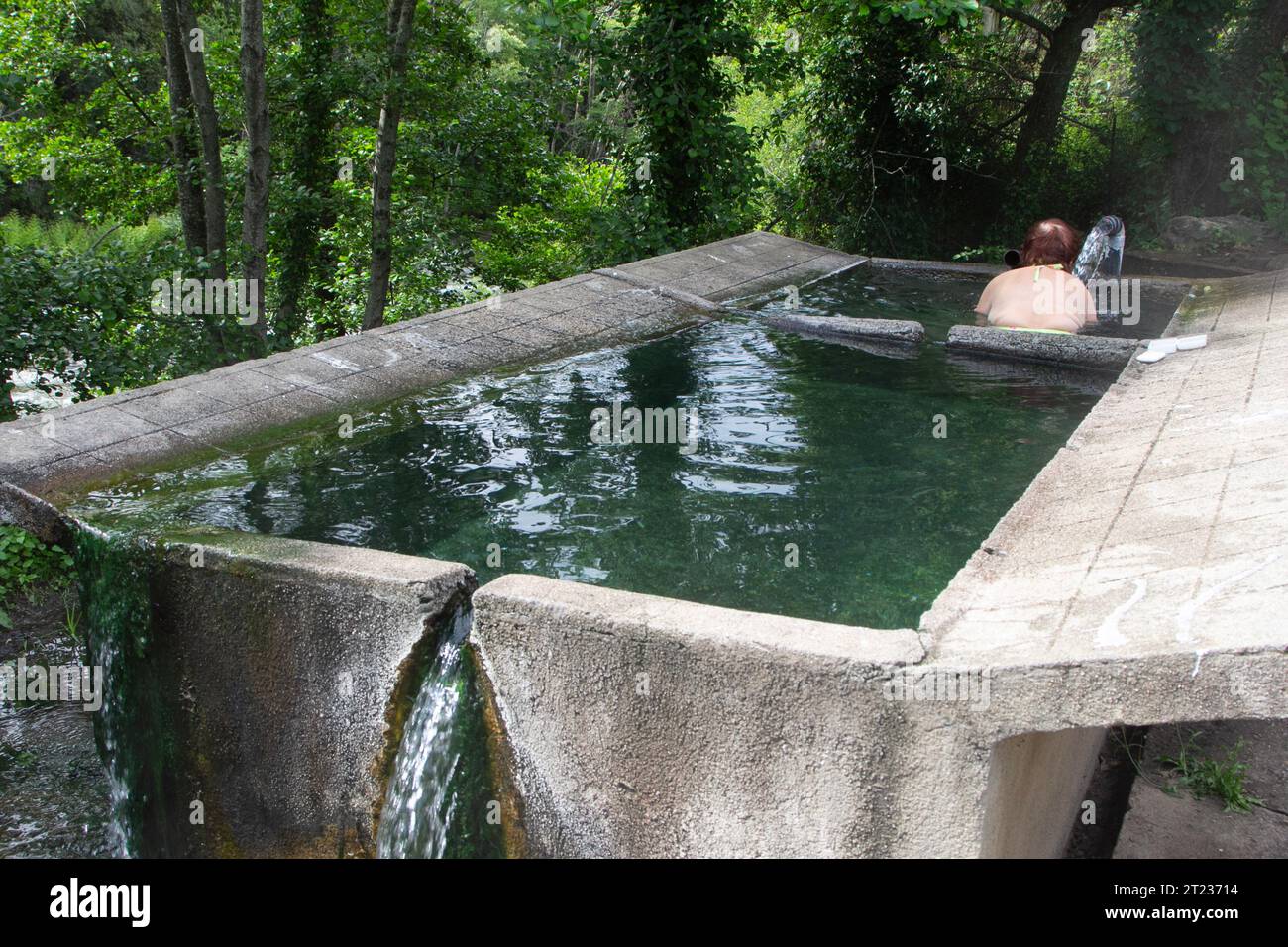 Corsica, Ghitera-les-Bains aka Bains de Guitera: a woman bathes in a trough filled with thermal water. Stock Photo