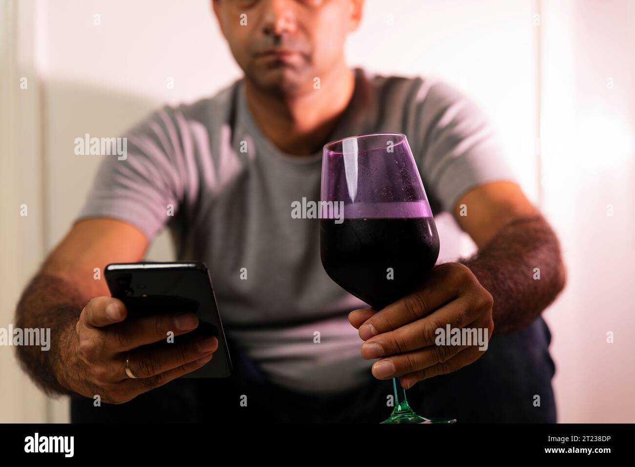 Bobo lifestyle of an unrecognizable caucasian man holding wineglass and texting from a smartphone. Stock Photo