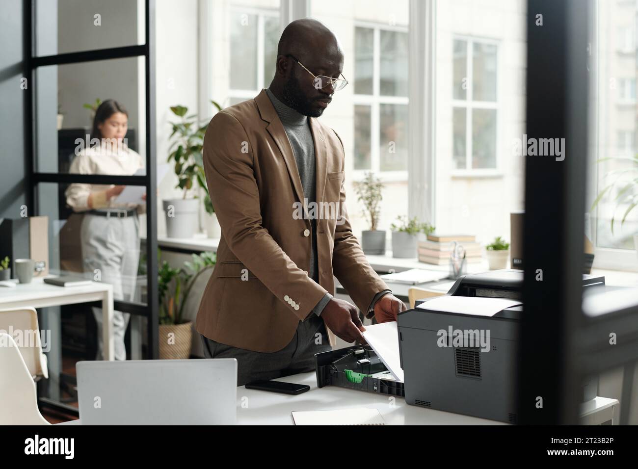 Young African American male office worker putting paper sheets into