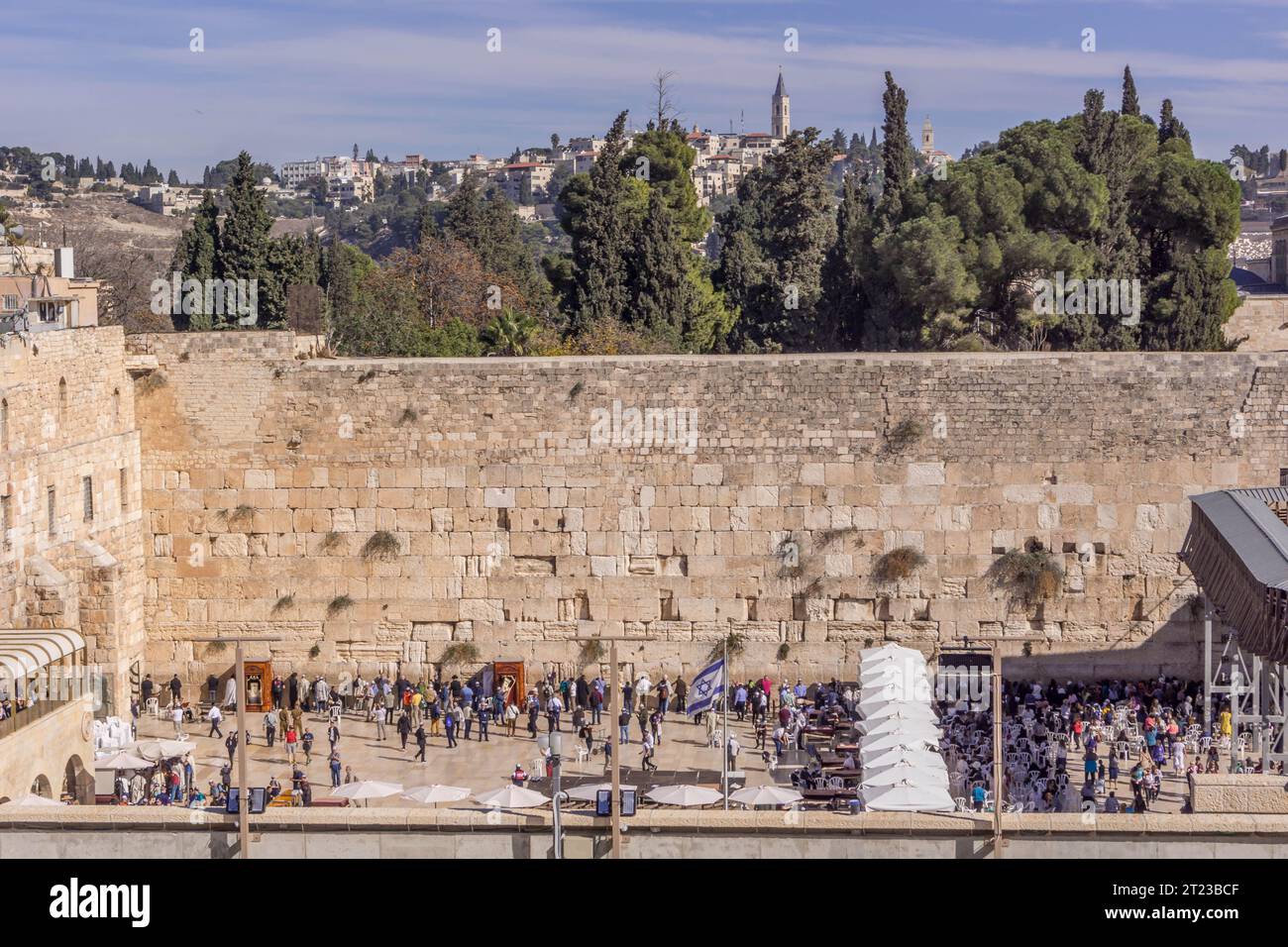 The Western Wall (Wailing Wall), the major Jewish shrine, with the pilgrims praying, the Israel flag, and barrier separating the woman's part of compl Stock Photo