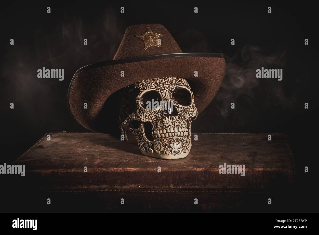A closeup shot of a skull with Mexican patterns wearing a cowboy hat on a wooden table Stock Photo