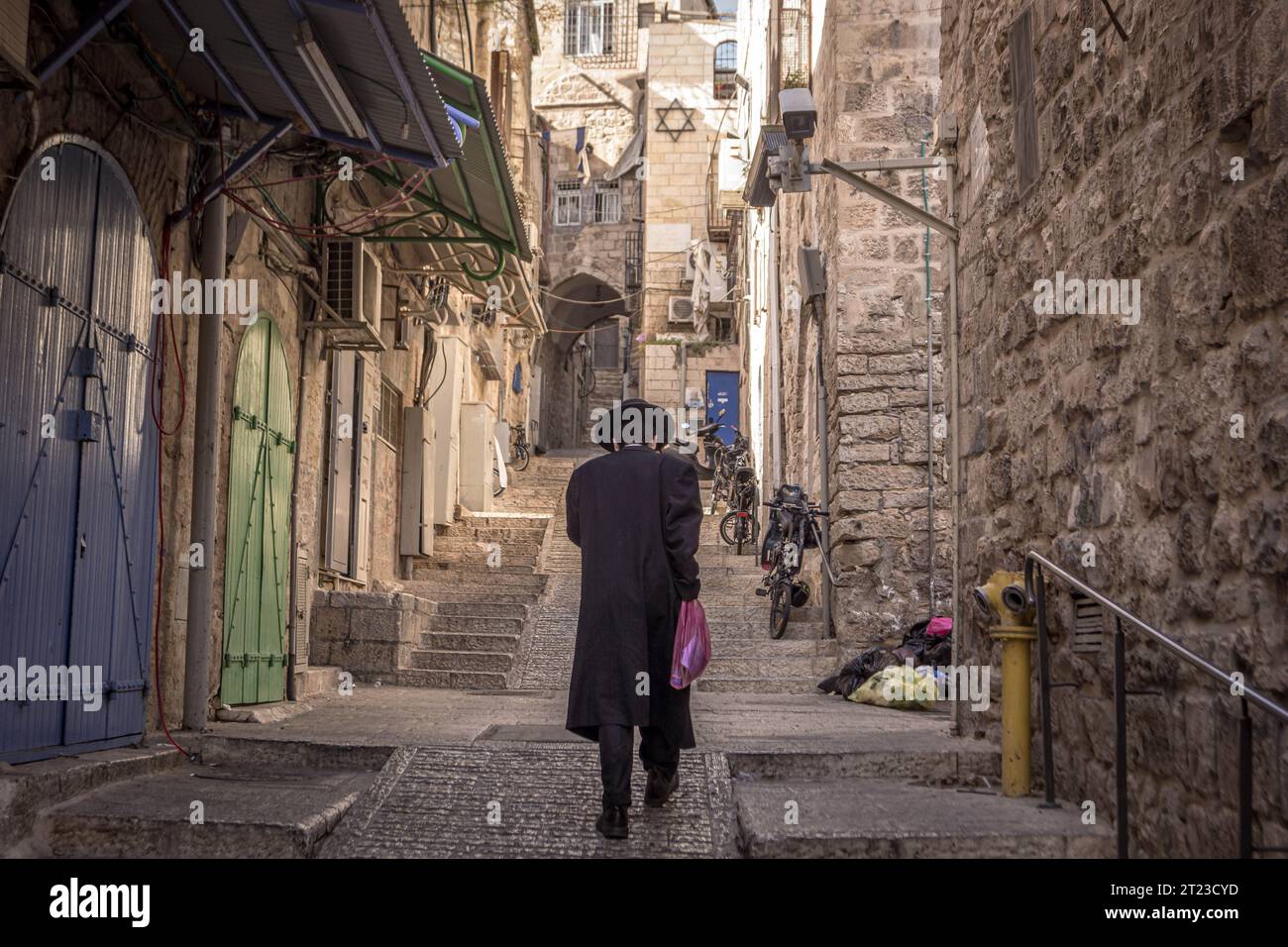 The haredi (ultra-Orthodox) Jewish man is walking down the empty street in the old  city of Jerusalem in Israel. Stock Photo