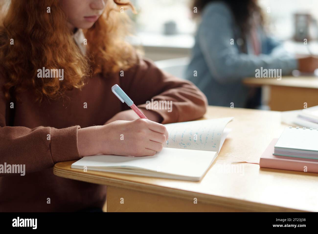 Hand of diligent schoolgirl with pen writing down new grammar rules of