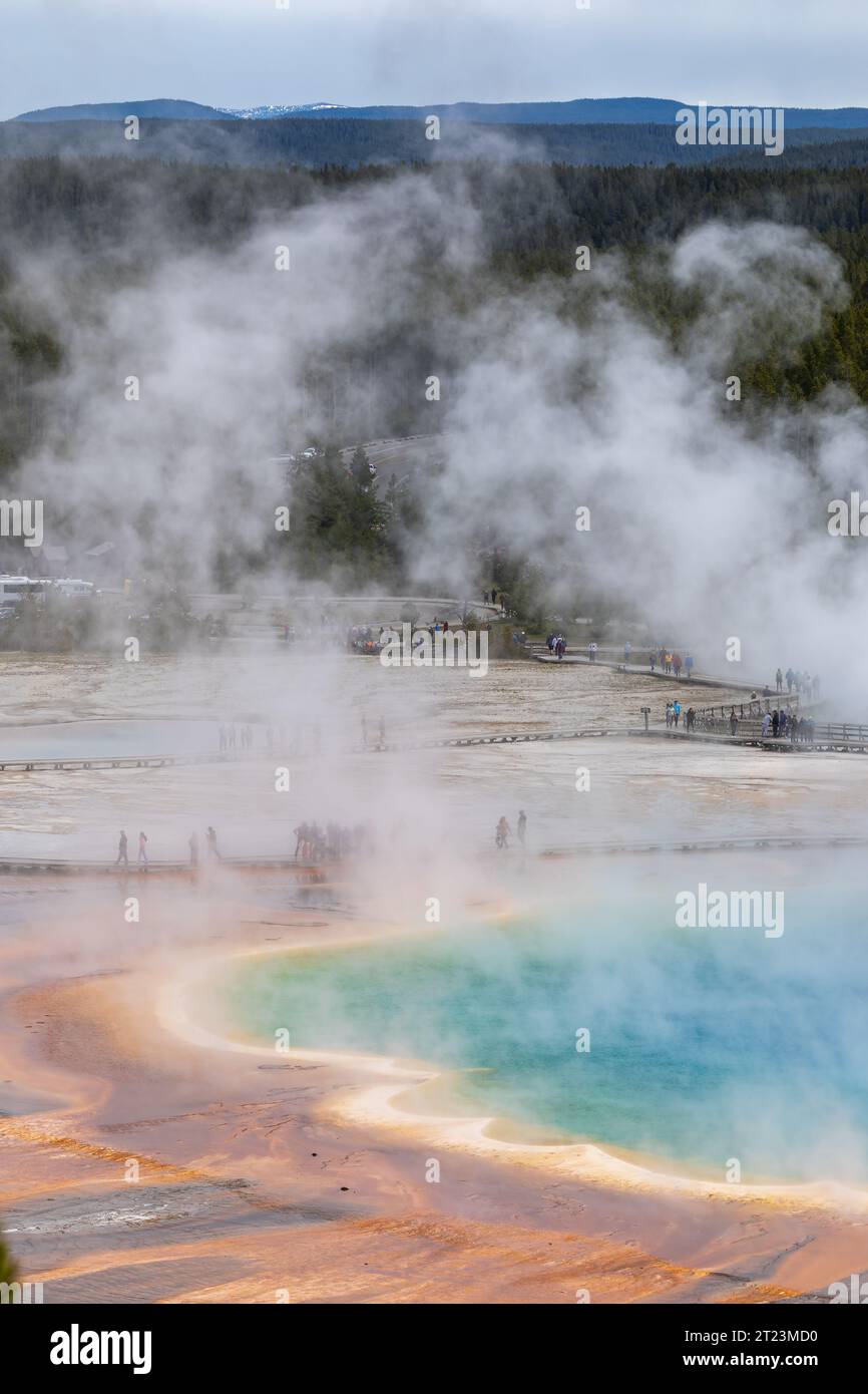 Tourists walk along boardwalk and view colorful blue pool of grand ...