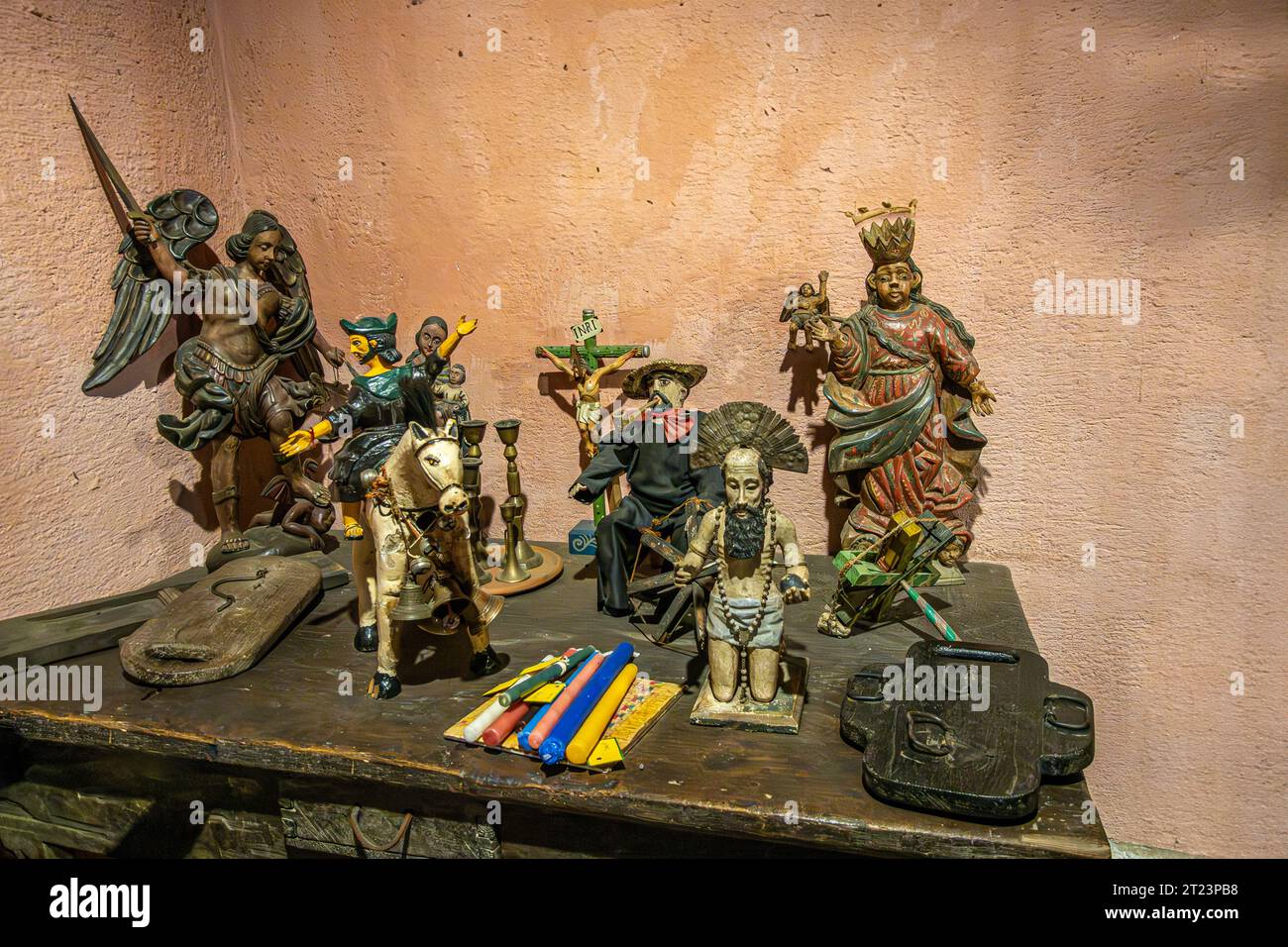 Guatemala, La Antigua - July 20, 2023: Finca La Azotea museums. Collection of small Catholic saint statue set together on dark wooden vintage cabinet. Stock Photo