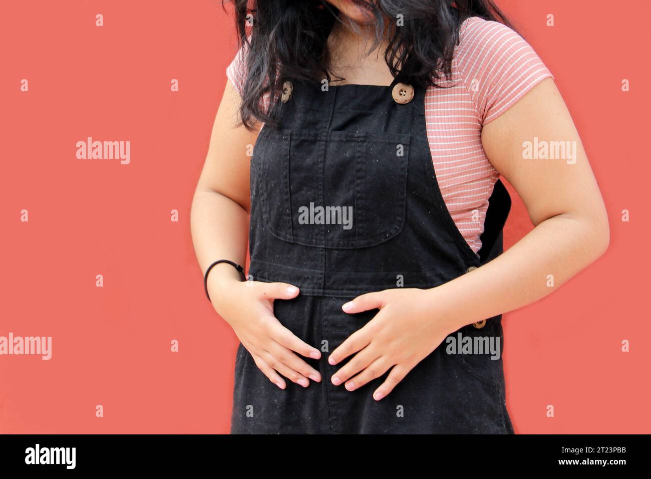 Teenage woman with early pregnancy appears sad, worried and in pain living in poverty and without education Stock Photo