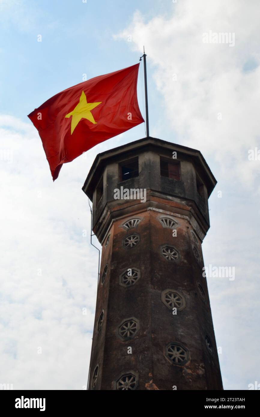 National flag of Vietnam flies proudly on a flagpole at the top of the famous watch tower or lookout in Hanoi, Vietnam Stock Photo