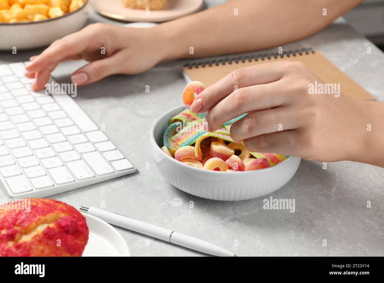 Bad habits. Woman eating jelly candies while working on computer at