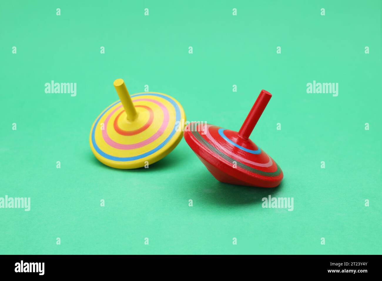 Two bright spinning tops on green background. Toy whirligig Stock Photo