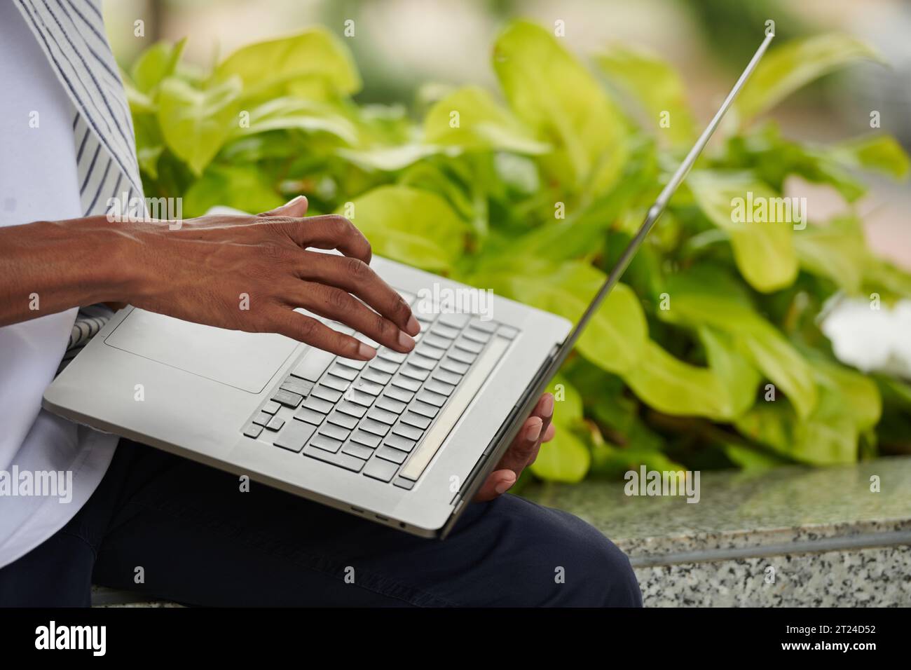 Closeup image of Black man working on laptop, coding and sending e-mails Stock Photo