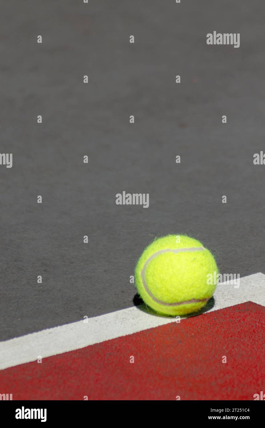 A vibrant yellow Tennis ball against the stark white court line Stock Photo