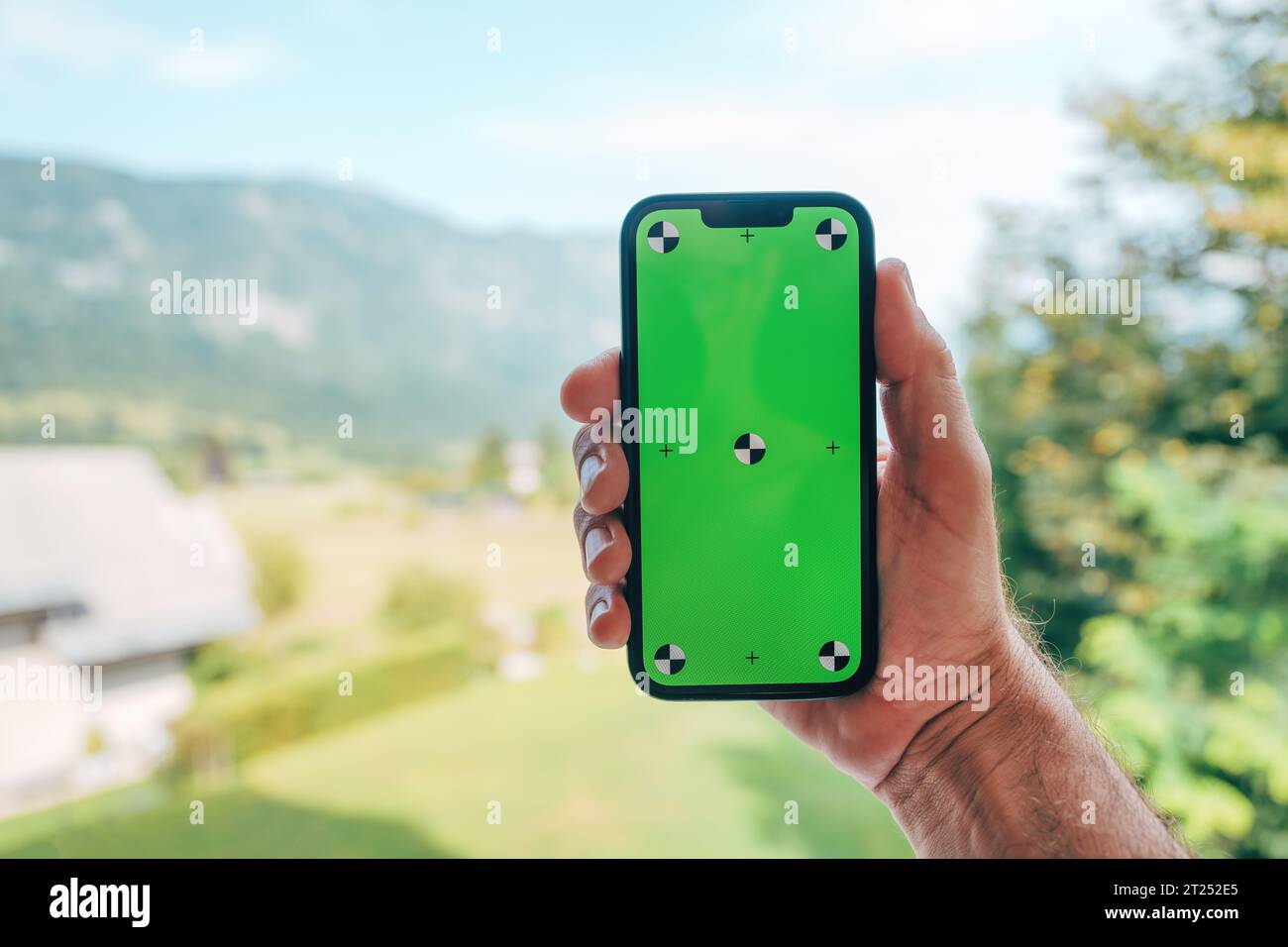 Male hand holding smart phone with mockup green screen, selective focus Stock Photo