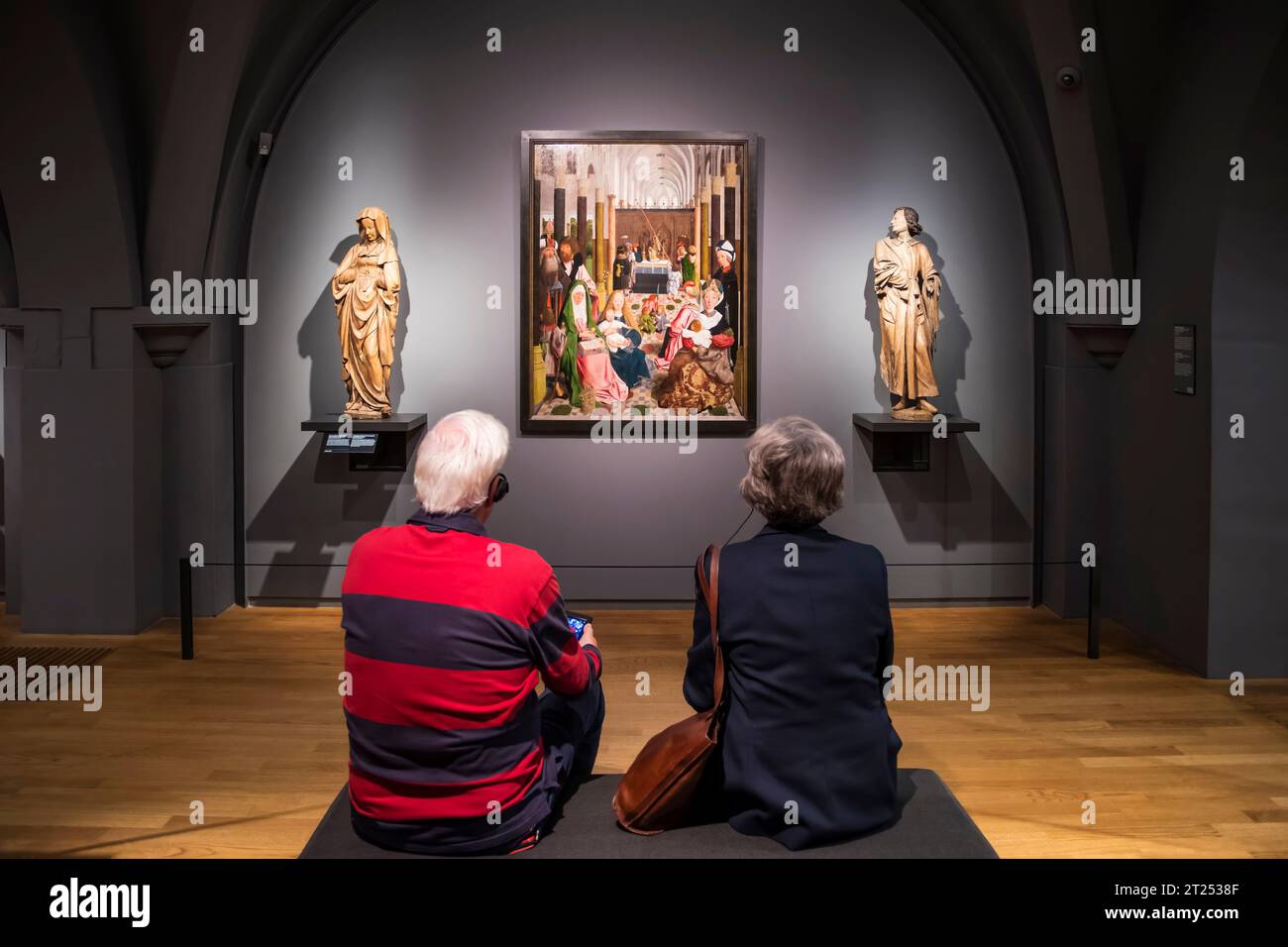 People listening to commentary & looking at The Holy Kinship, by the workshop of Geertgen tot Sint Jans, from 1495 in the Rijksmuseum, Amsterdam. Stock Photo