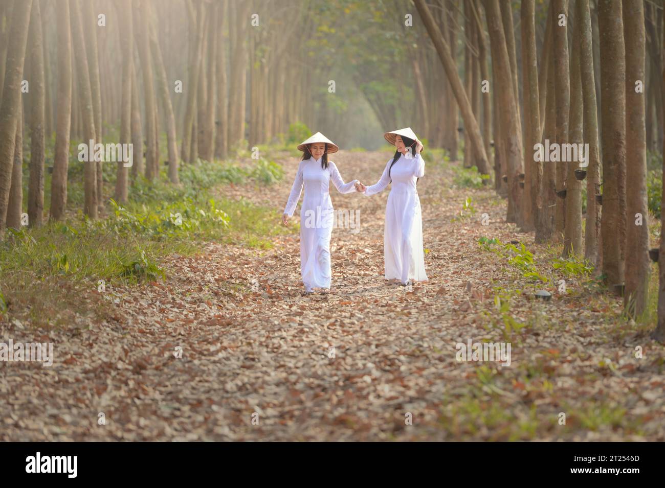 Two Asian woman in traditional clothing walking in a forest holding