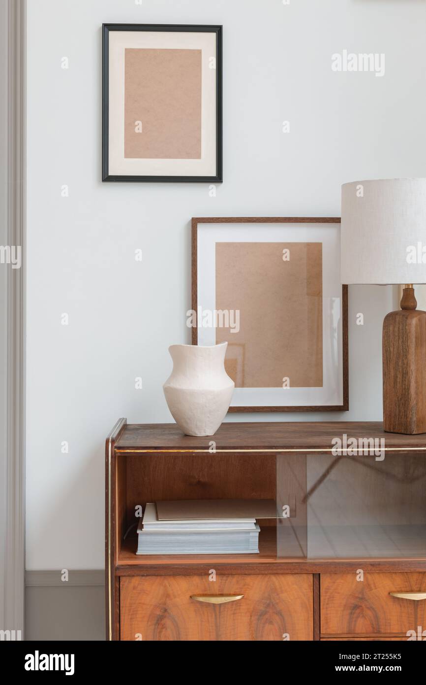 Blank picture frames hanging on a wall by a stylish sideboard in a living room Stock Photo