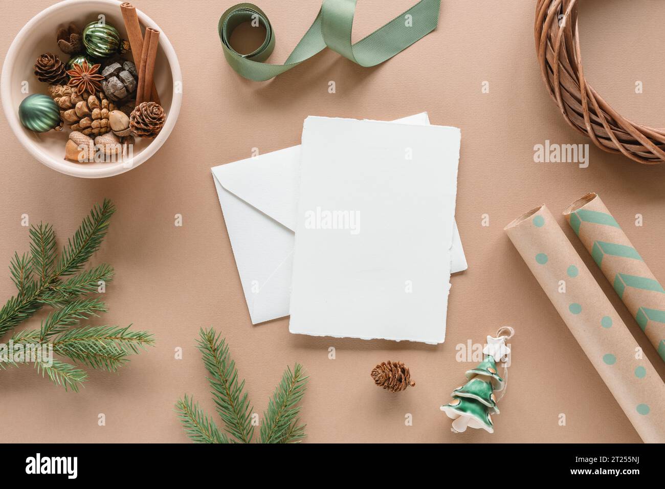Overhead view of a wrapped gift box, blank card, wrapping paper, ribbon and Christmas decorations Stock Photo
