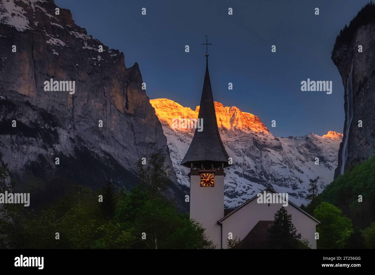 Church steeple against mountain backdrop at sunset, Lauterbrunnen, Bern, Switzerland Stock Photo
