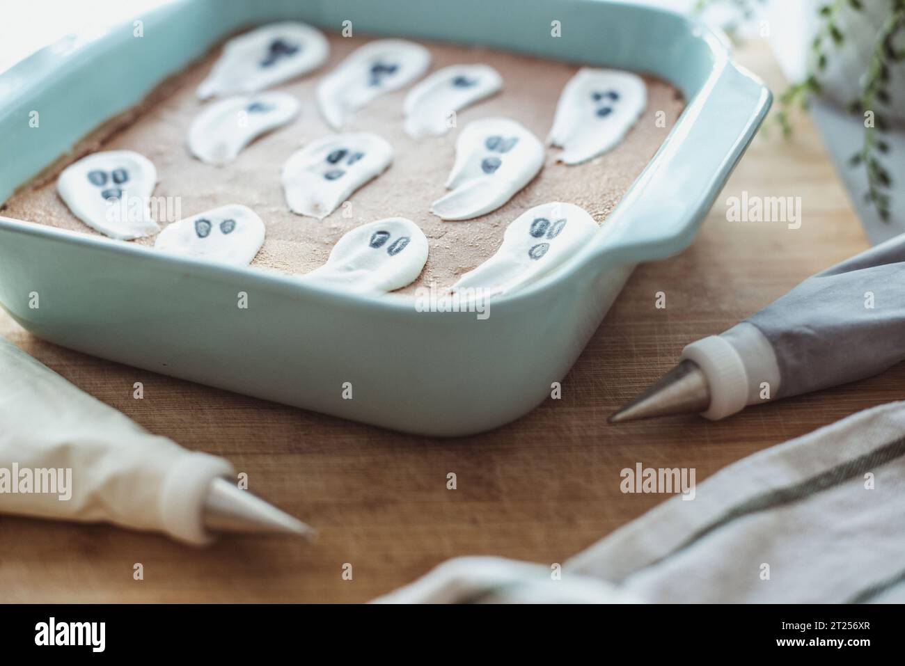Chocolate brownie Halloween cake with ghost icing decorations on a table with icing bags Stock