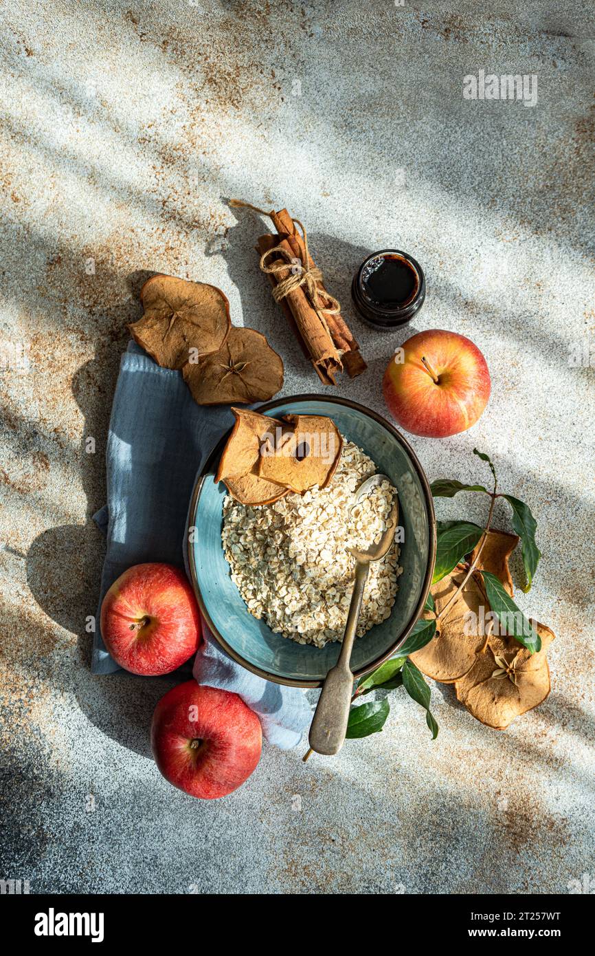 Overhead view of a bowl of Raw oats with fresh and dried apples, jam and cinnamon sticks Stock Photo