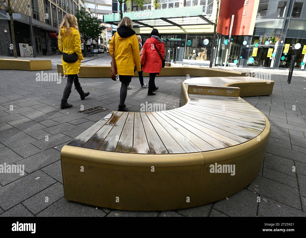 Wuppertal, Germany. 16th Oct, 2023. Passers-by walk past the shiny gold benches in the pedestrian zone of Elberfeld. In its 51st Black Book, the Taxpayers' Association has listed 100 exemplary cases nationwide which, according to its research, represent a waste of taxpayers' money. The enumeration presented on Tuesday nearly 200 sides strong contains also 13 cases from North Rhine-Westphalia. Among the most astonishing examples are uncomfortable but golden benches in Wuppertal's city center. Credit: Roberto Pfeil/dpa/Alamy Live News Stock Photo
