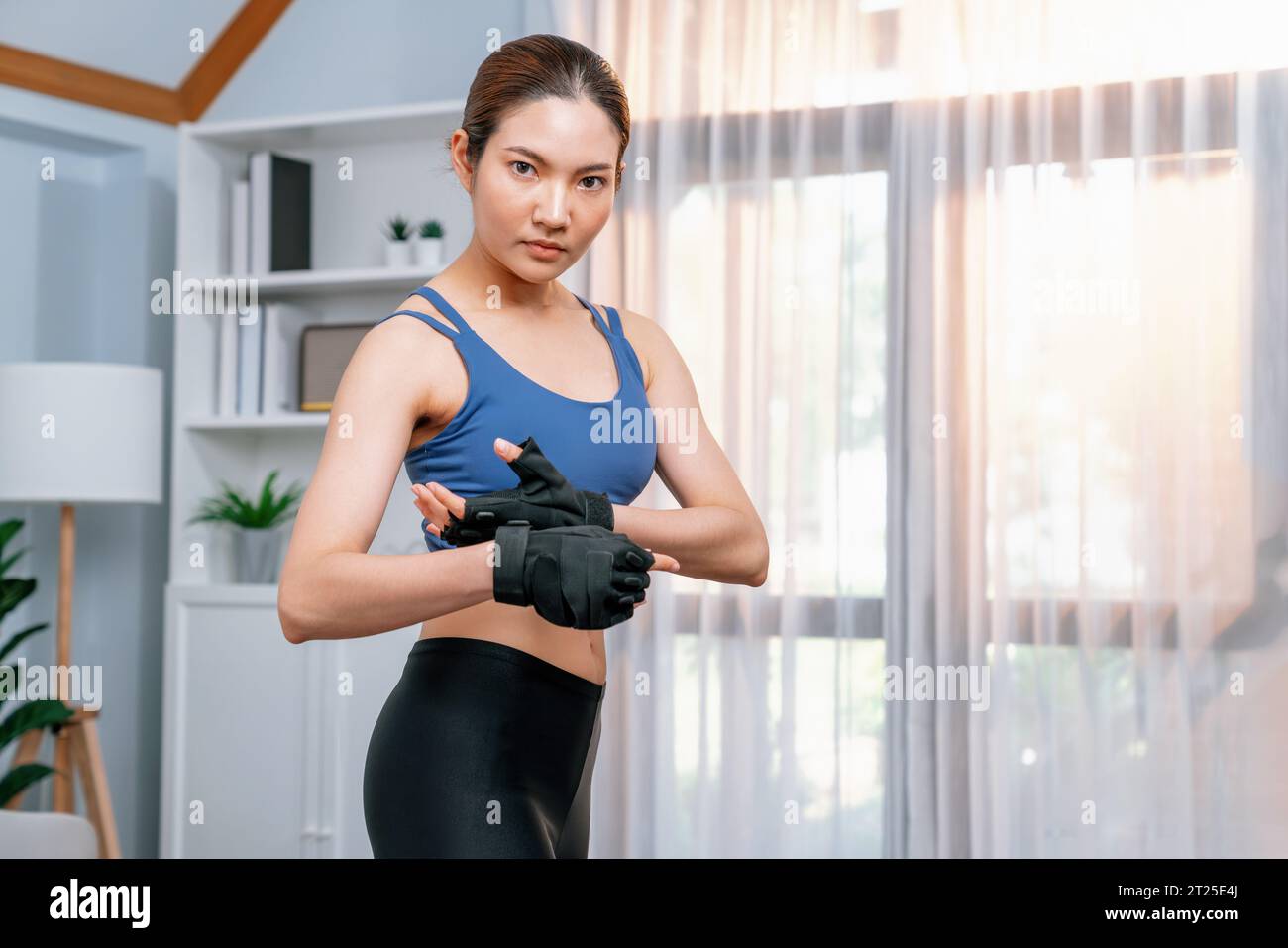 Fit young asian woman portrait in sportswear preparing herself before healthy exercising routine at home. Domestic fitness workout training on living Stock Photo