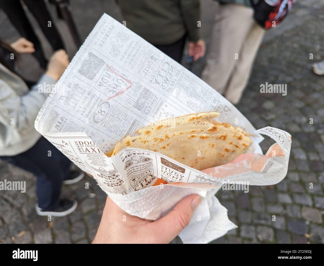 A close-up of a man holding a freshly-made crepe in a Parisian street, in France Stock Photo