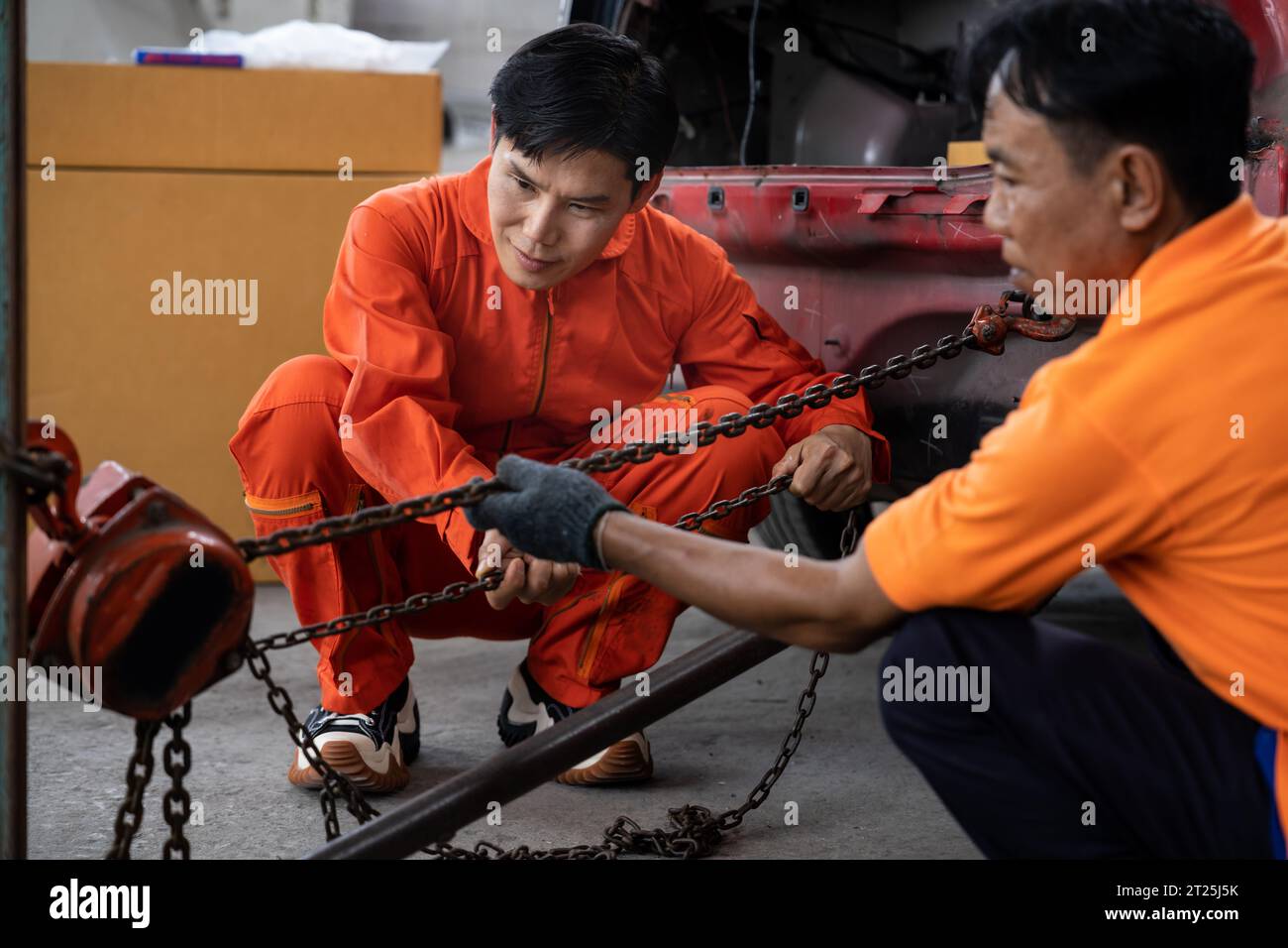 Mechanic testing strength and reliability of chain hoist for car towing