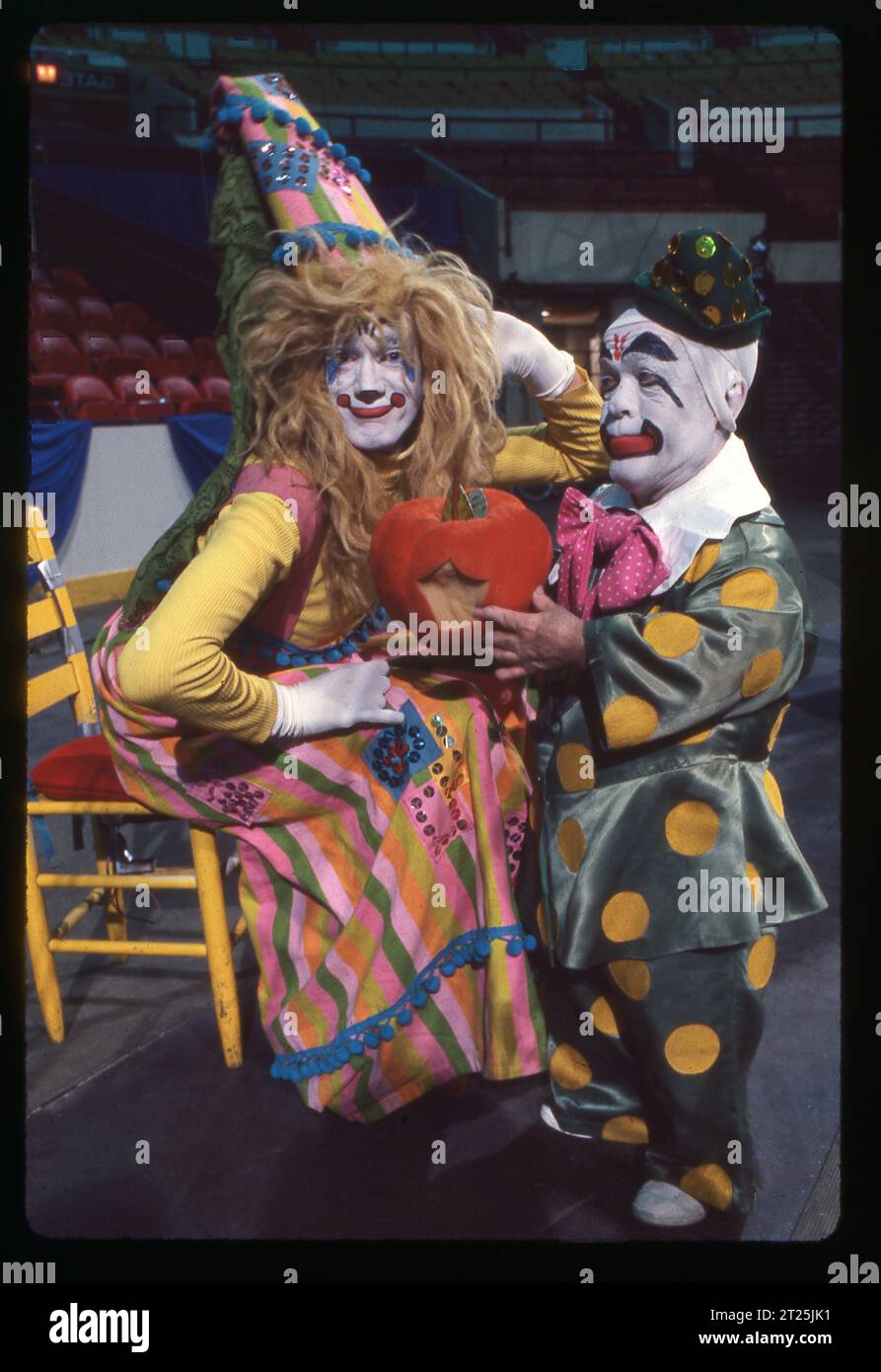 Photo of 2 Ringling Brothers clowns in full makeup holding a pumpkin that seems to have been bitten. At Clown College auditions in 1979. The clown to the right is Prince Paul. Stock Photo