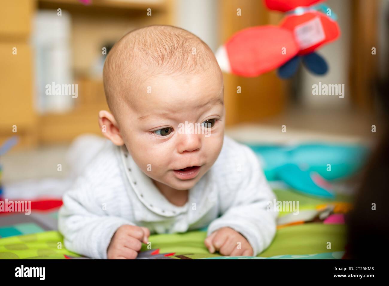 Newborn baby spending tummy time in their playground, baby gym to develop motor skills and