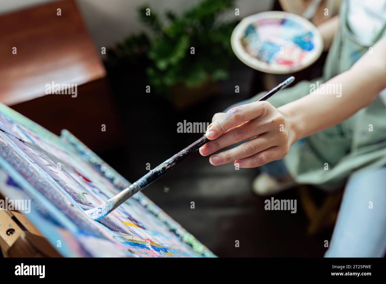 Female artist hold color palette and paintbrush for painting during ...