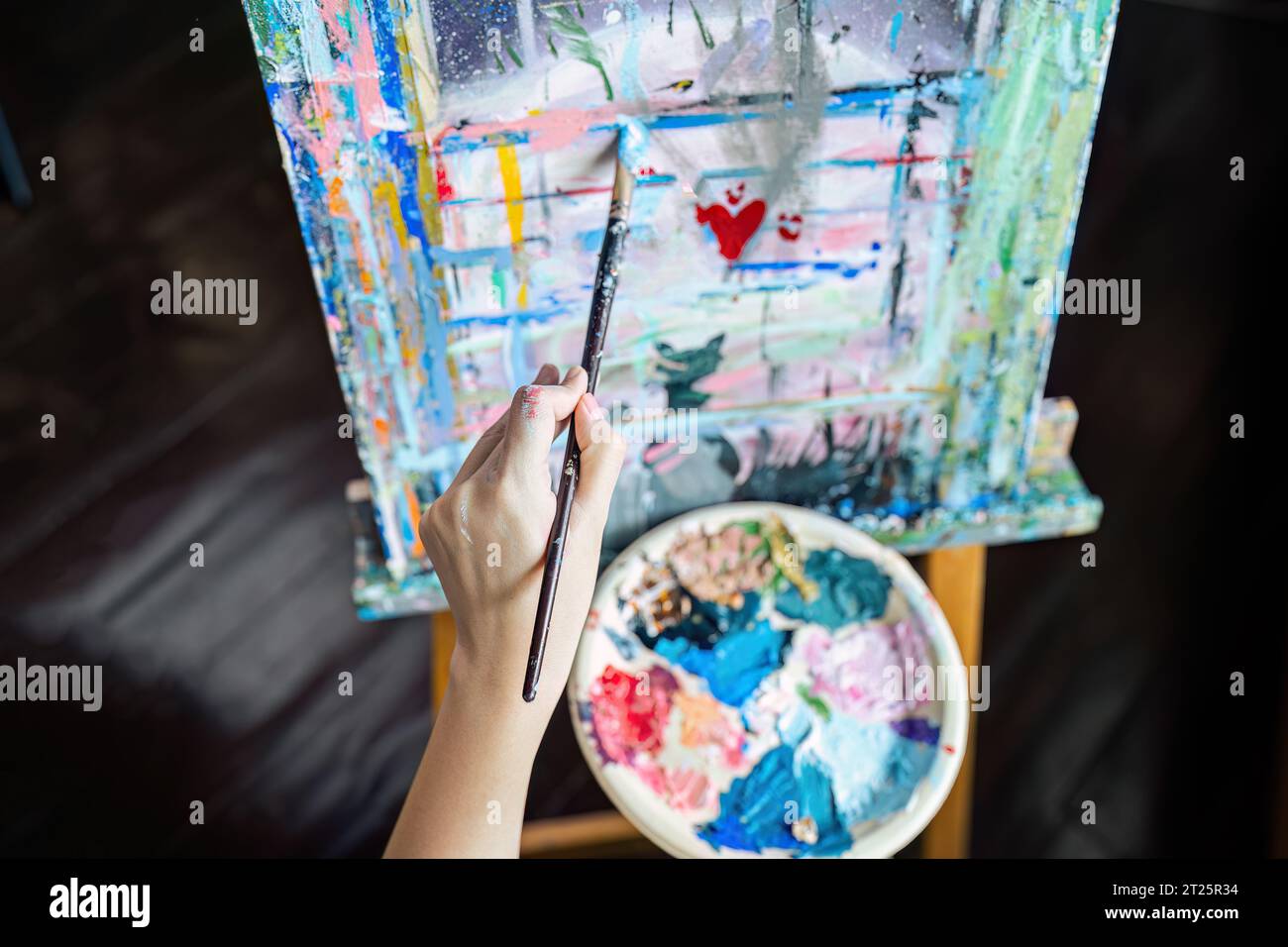 Female artist hold color palette and paintbrush for painting during ...