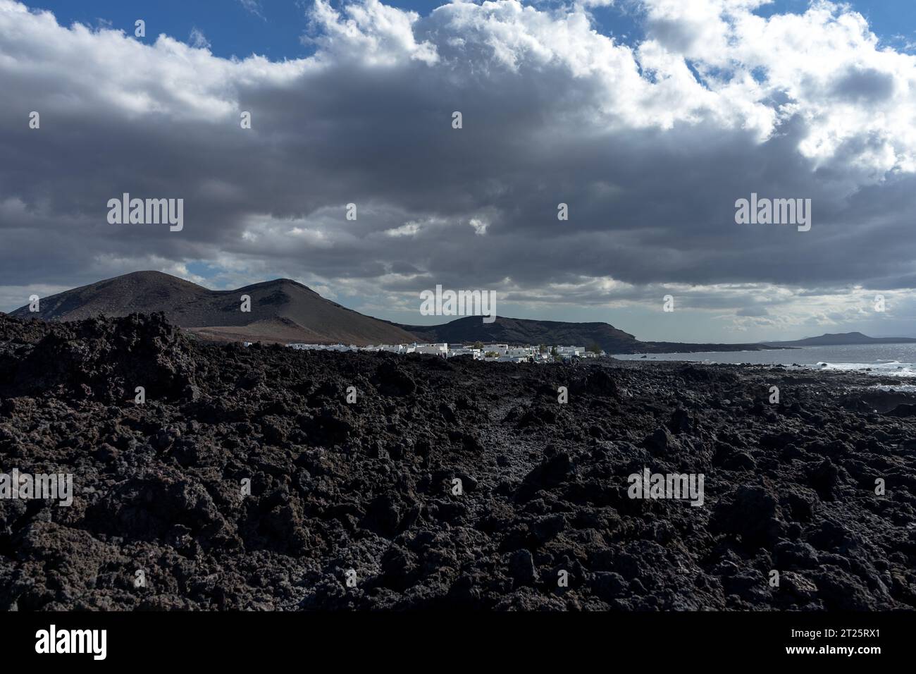 Spain, Lanzarote: lava field with the village of El Golfo in the background Stock Photo