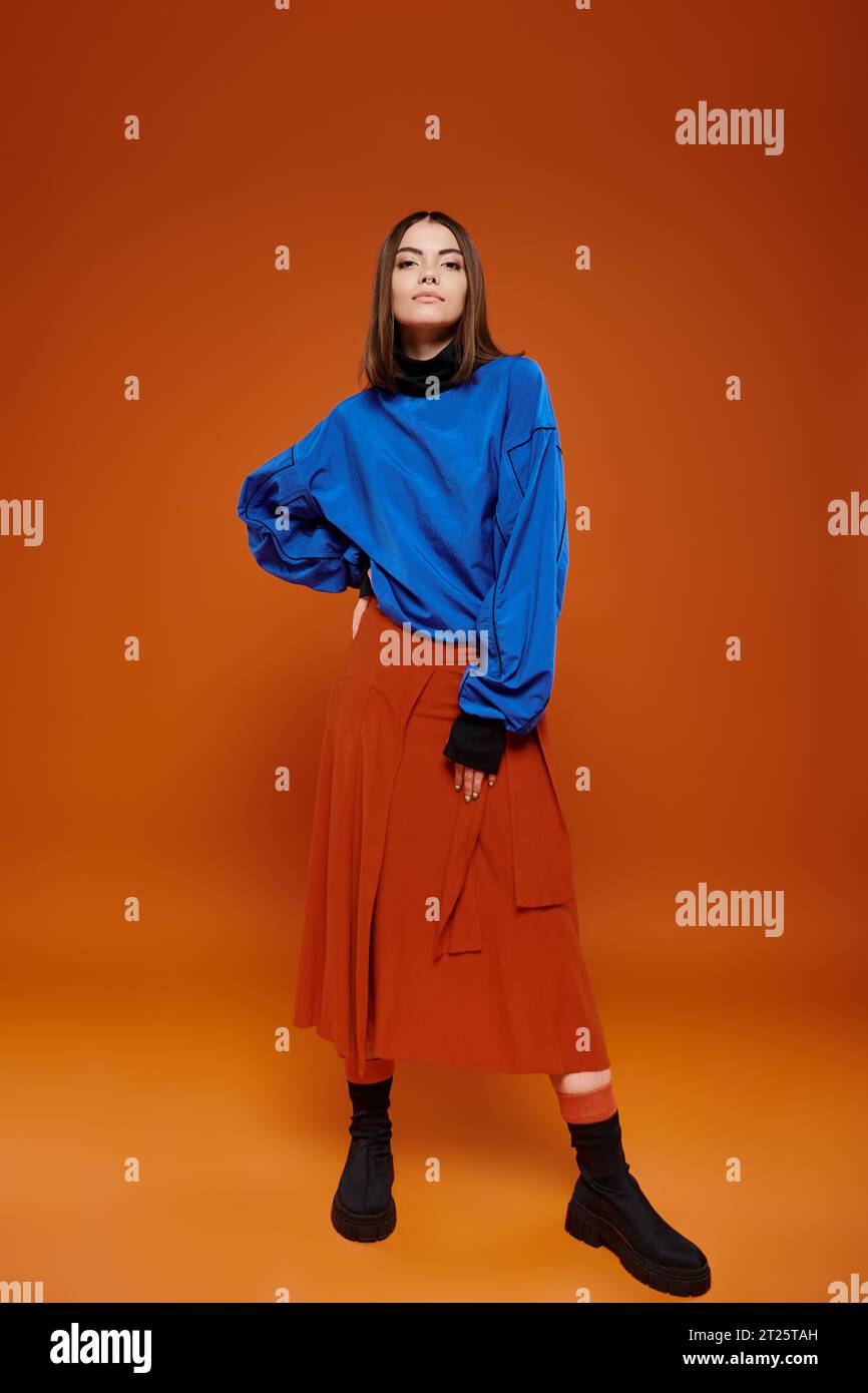 attractive young female model wearing casual blue jacket and orange skirt with her hand on hip Stock Photo