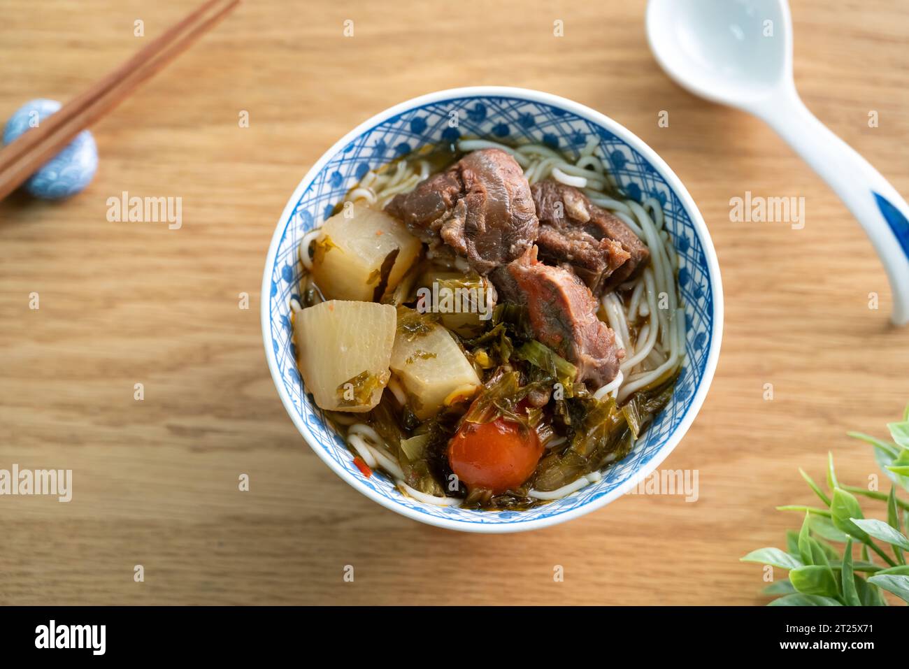 Beef noodle soup. Taiwanese famous food with sliced red braised beef and vegetables in a bowl on wooden table background. Stock Photo