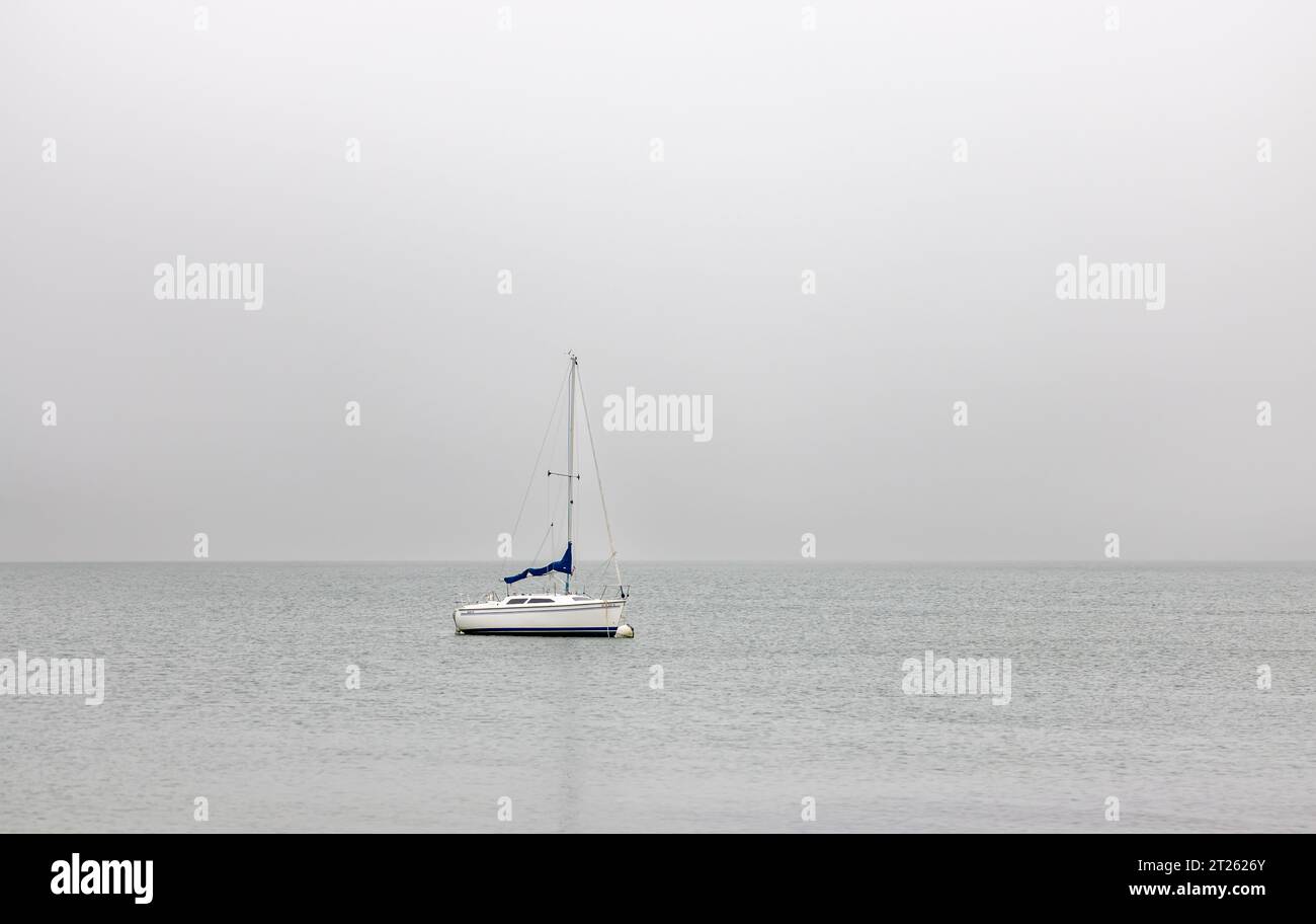 a single sail boat, bella II on a mooring on a gray day in montauk Stock Photo