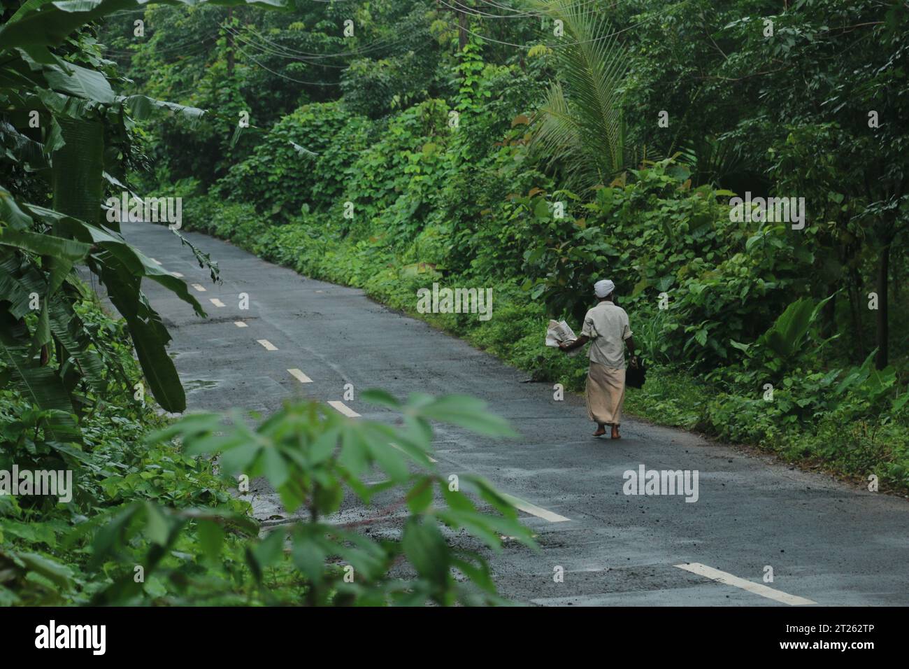 An old man walking on the road early morning in Kerala. Stock Photo